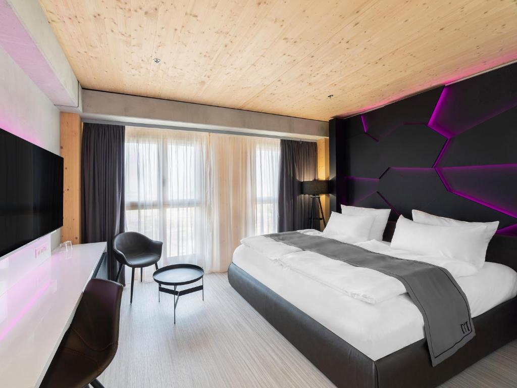 een slaapkamer met een groot bed met een paars hoofdeinde bij DORMERO HoHo Wien in Wenen