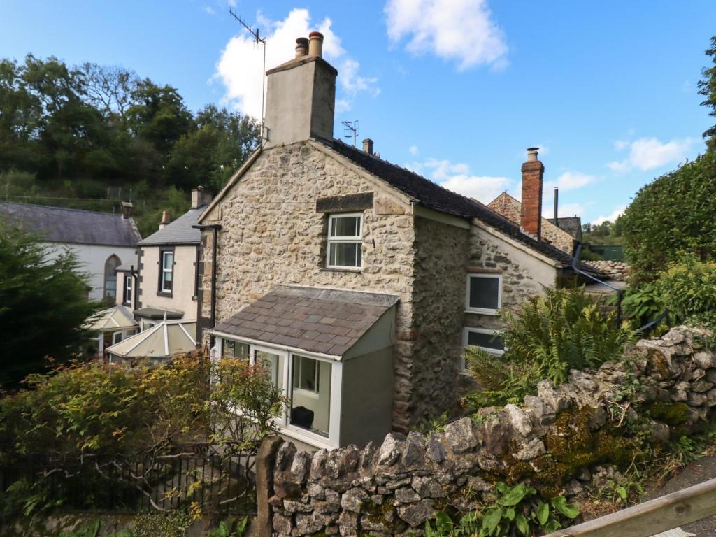 een oud stenen huis met een stenen muur bij Park Cottage in Matlock