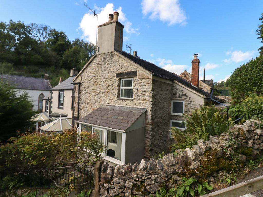 an old stone house with a stone wall at Park Cottage in Matlock