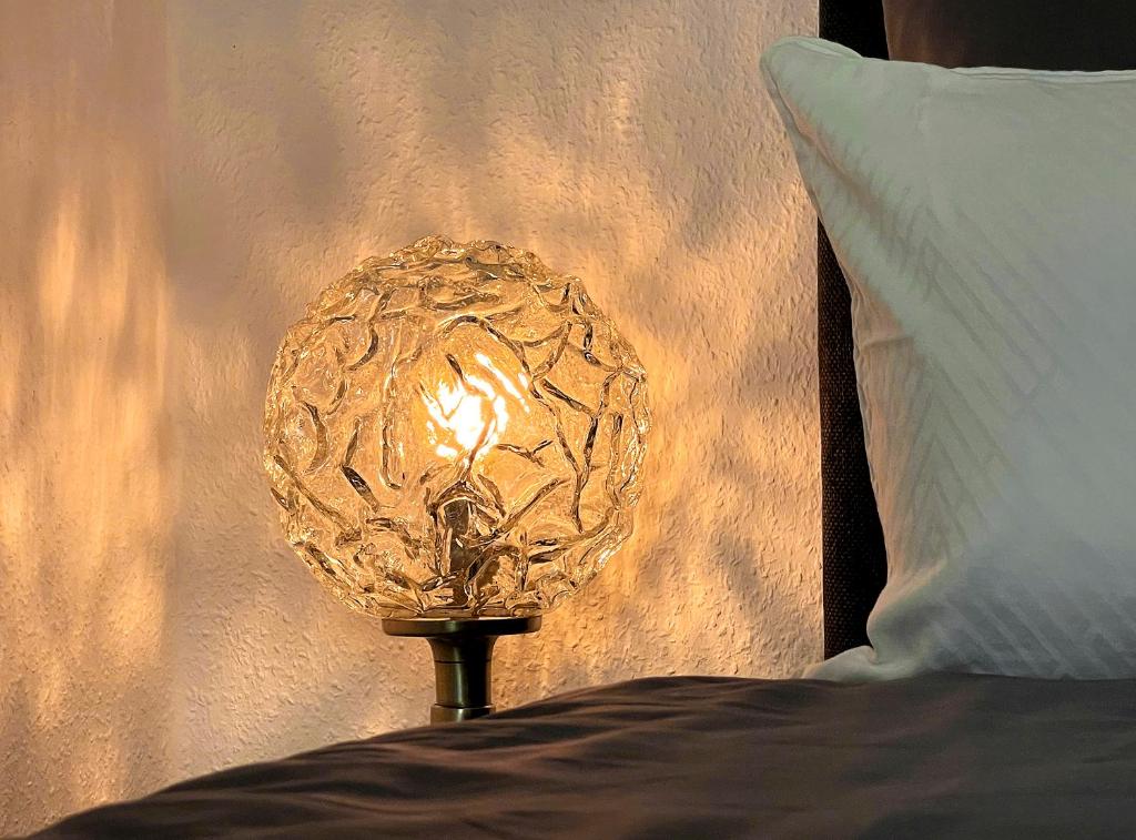 a gold lamp sitting on a bed next to a pillow at SPACE AGE Design-Luxus-Apartment, Terrasse, Zentral in Gera