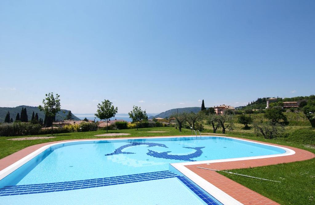 a large swimming pool in a field with a hill in the background at Appartamenti I Cortivi in Costermano