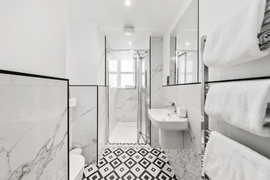a white bathroom with a shower and a sink at Commodore Hotel in London