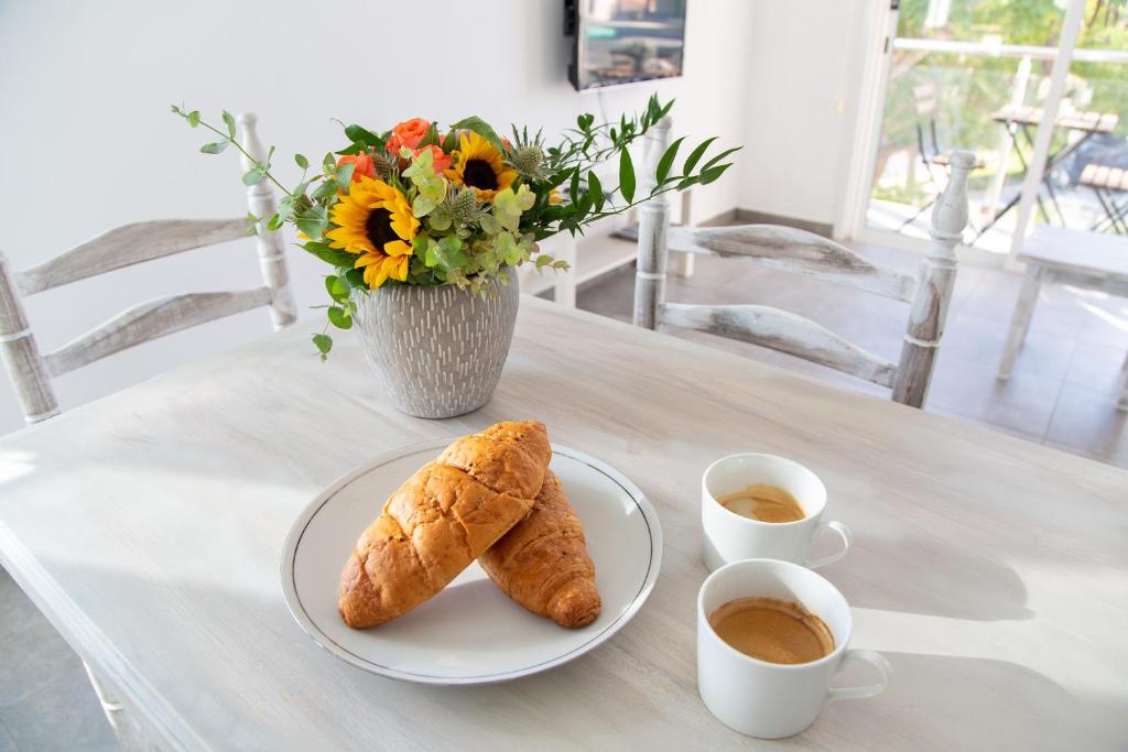 a table with a plate of croissants and cups of coffee at Tikay Holiday Apts in Ayia Napa