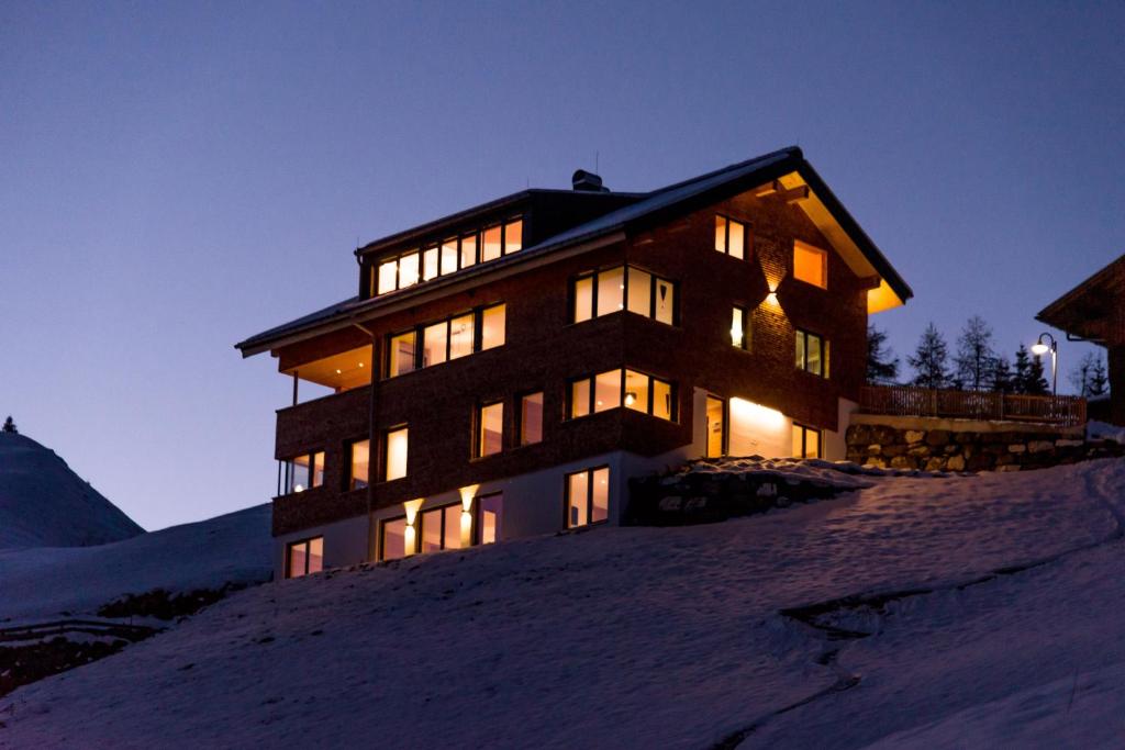 um edifício no topo de uma colina coberta de neve em Bildegg Appartements em Warth am Arlberg