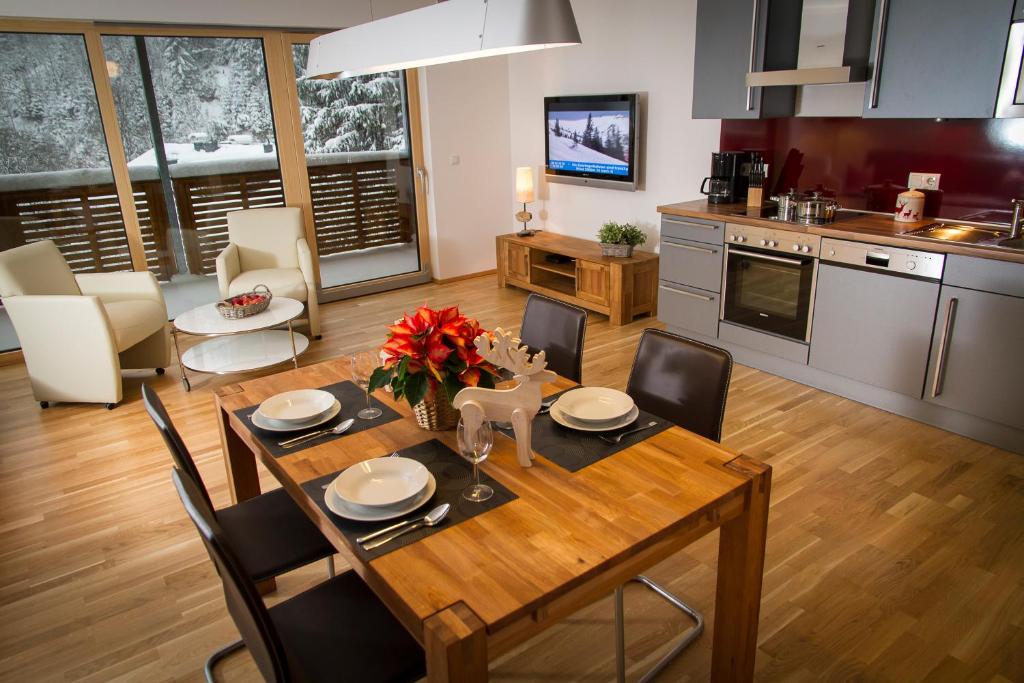 Il comprend une cuisine et une salle à manger avec une table et des chaises en bois. dans l'établissement Steinbock Superior Appartement, à Zell am See