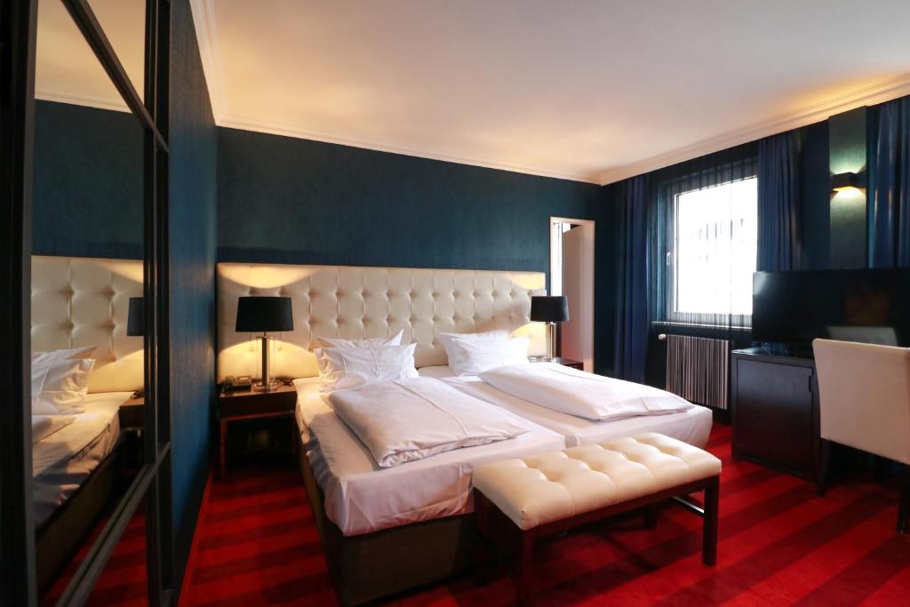 a bedroom with a large white bed and a mirror at Hotel Haverkamp in Bremerhaven