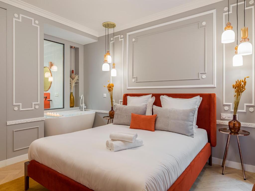 um quarto com uma cama grande e uma casa de banho em The Orange Haussmann em Paris