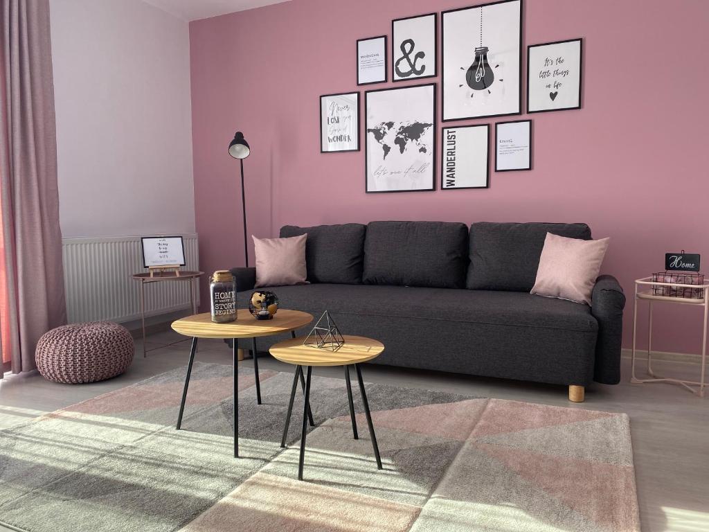 uma sala de estar com um sofá e duas mesas em Wanderlust Home Pink, Rasnov Apt for 4, Wifi and Free Parking em Rasnov