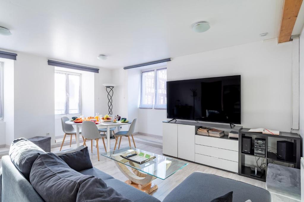 ein Wohnzimmer mit einem Sofa, einem TV und einem Tisch in der Unterkunft Gite Le Carpe Diem - Classé 3 étoiles - Centre ville - Wifi - Netflix in Marmoutier