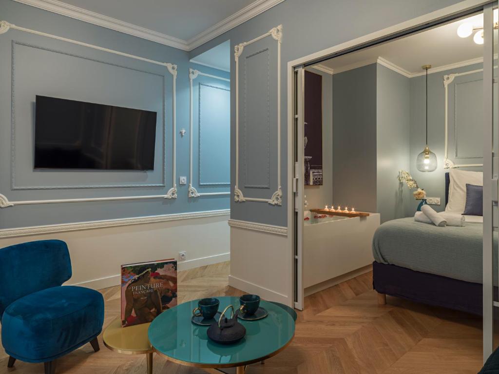 une chambre avec un lit, une table et une télévision dans l'établissement The Pompadour Suite, à Paris
