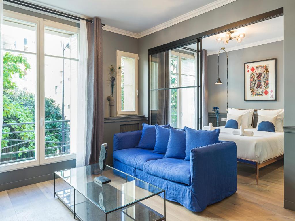 uma sala de estar com um sofá azul e uma cama em The Blue King Suite em Paris