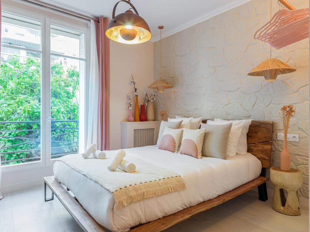 um quarto com uma grande cama branca com almofadas em Pink & Wood cocoon em Paris