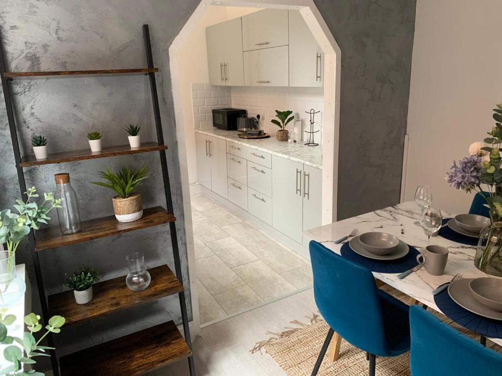 a kitchen and dining room with a table and blue chairs at House of cosy dots in Northampton