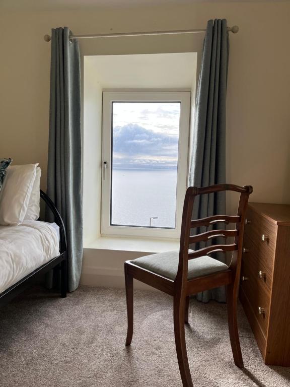 a bedroom with a bed and a chair and a window at Old Irish farmhouse in Dingle