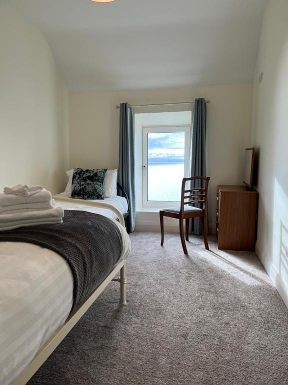 a bedroom with two beds and a chair and a window at Old Irish farmhouse in Dingle