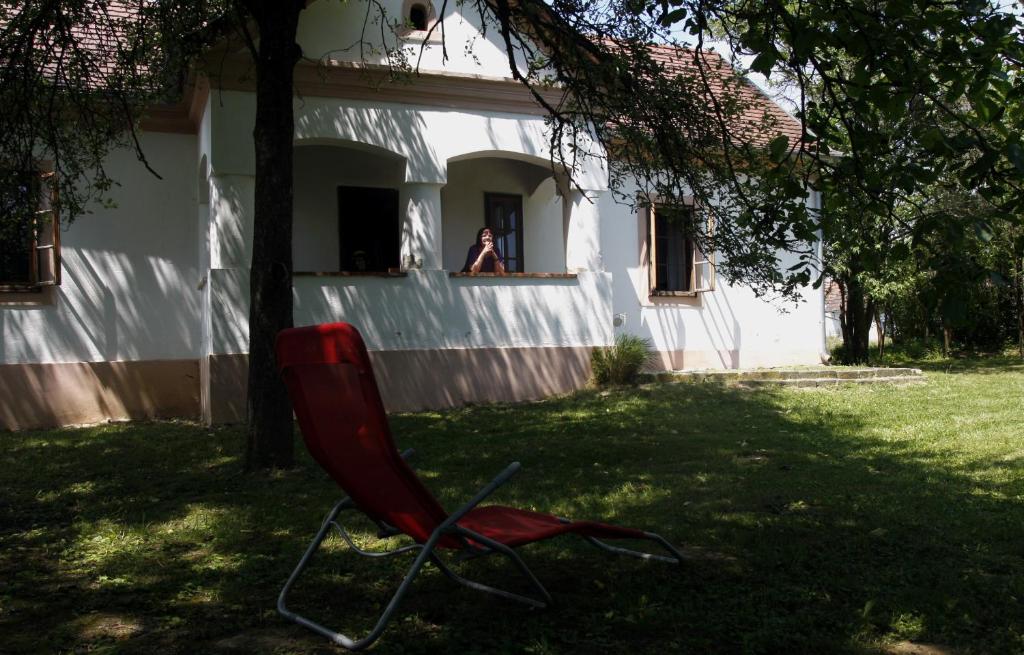 una silla roja sentada en el césped frente a una casa en Alinda apartman, en Magyarszombatfa
