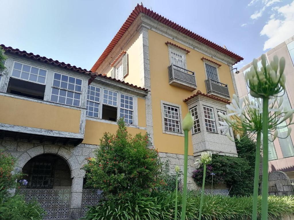 a yellow house with windows and a courtyard at Camelia Rooms in Guimarães