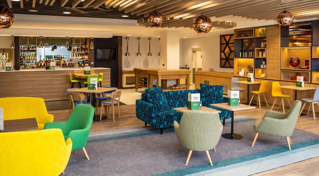 レスターにあるHoliday Inn - Leicester - Wigston, an IHG Hotelのカラフルな家具、テーブル、椅子が備わるレストランを併設しています。