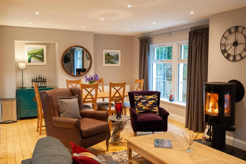 a living room with chairs and a table and a fireplace at Parkside, The Loch Ness Cottage Collection in Inverness