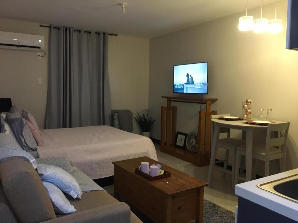 a living room with a bed and a couch and a tv at Cozy Condo in Saekyung 956 with FREE HIGHSPEED Internet connection in Mactan