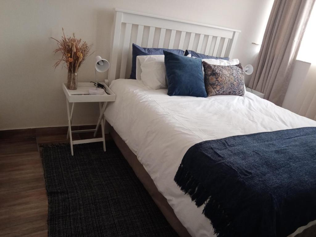 een bed met blauwe kussens en een nachtkastje met een tafel bij Private Room Chez Khanyi Homestays in Pretoria
