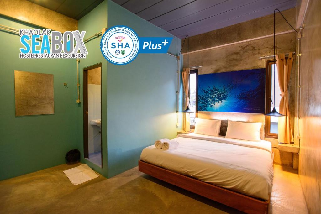 a bedroom with a bed and a sign that says sea boy plus at Seabox Khaolak Hostel in Khao Lak