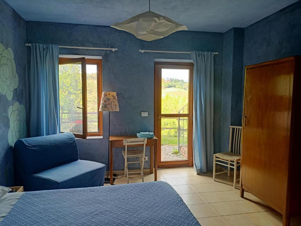 a bedroom with a bed and a chair and a window at I Conti della Serva in Cinzano