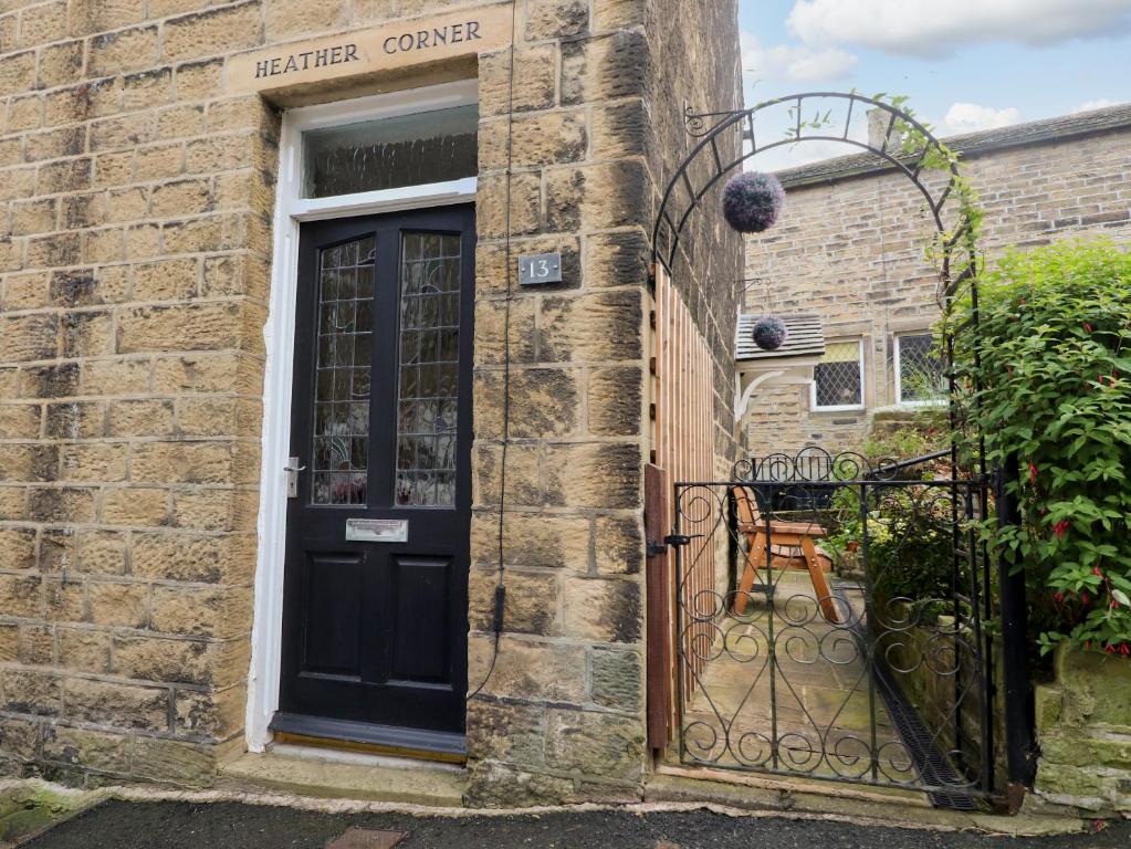 a black door on a brick building with a gate at Heather Corner in Keighley