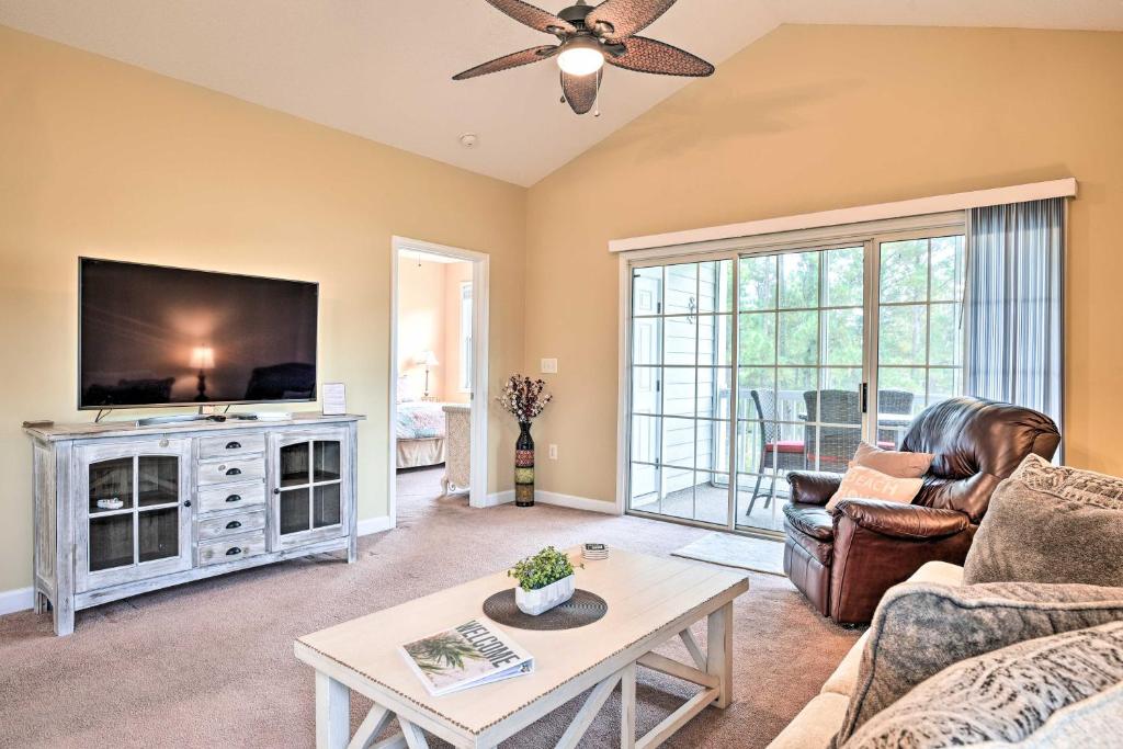 a living room with a tv and a couch and a table at Bright and Airy Resort Condo Golf, Shop and Swim in North Myrtle Beach