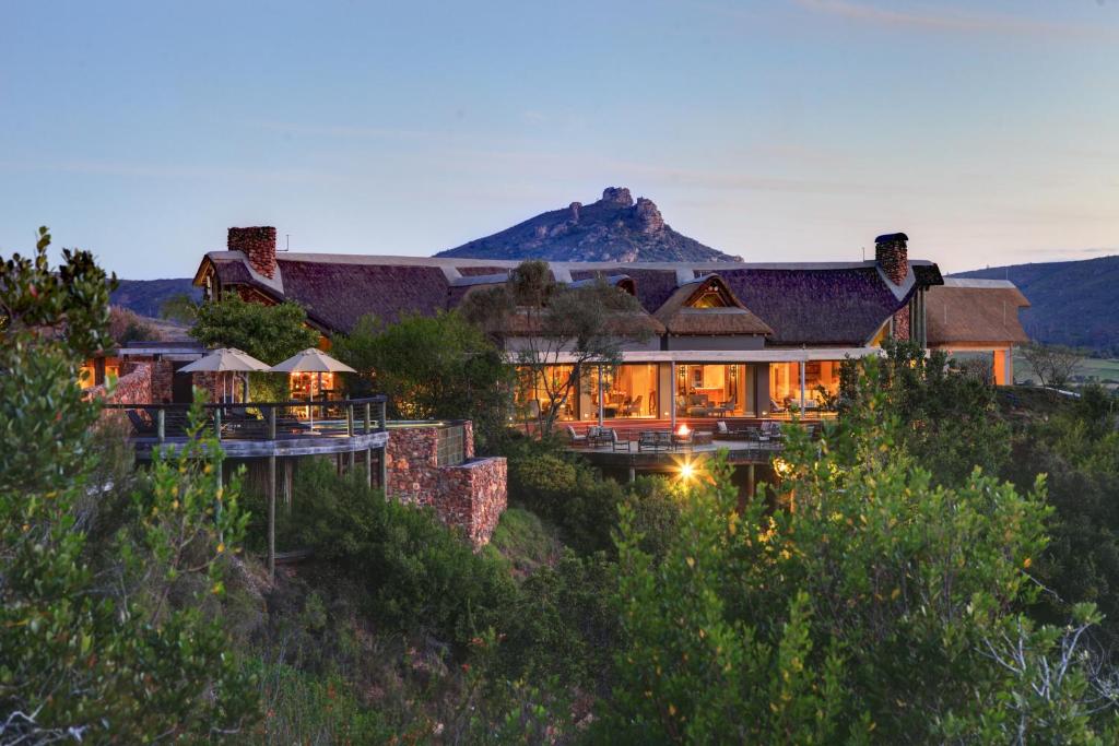 a house on a hill with a mountain in the background at Botlierskop Private Game Reserve in Reebok