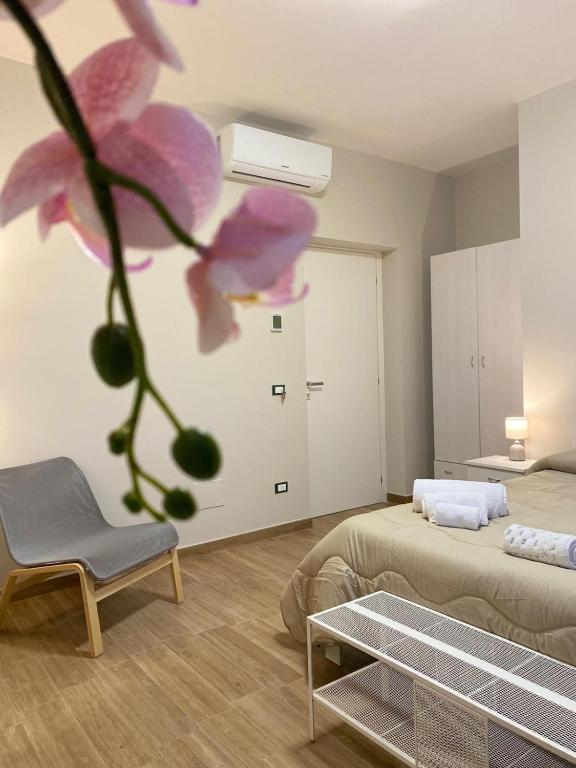Pokój z 2 łóżkami, krzesłem i kwiatem w obiekcie B&B Ercole Agrigento w mieście Villaggio Mosè
