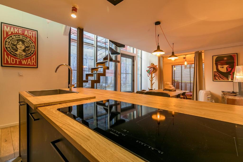 a kitchen with a counter with a sink and a living room at L'ATELIER DU CHAPEAU ROUGE EN PLEIN CENTRE VILLE in Dijon