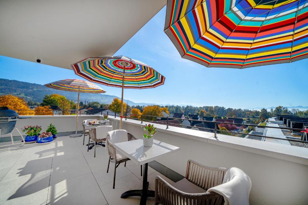 bodenseezeit Apartmenthotel Garni في لينداو: بلكونه فيها طاولات وكراسي ومظلات