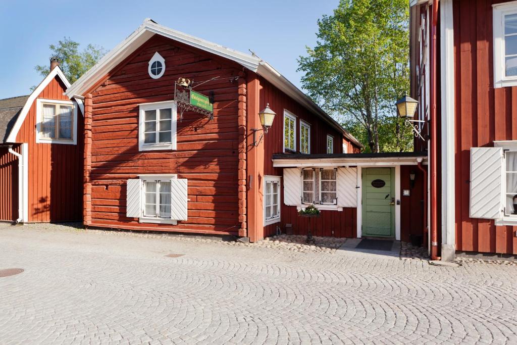 ein Holzhaus in einer Kopfsteinpflasterstraße neben einem Gebäude in der Unterkunft Grythyttans Gästgivaregård in Grythyttan