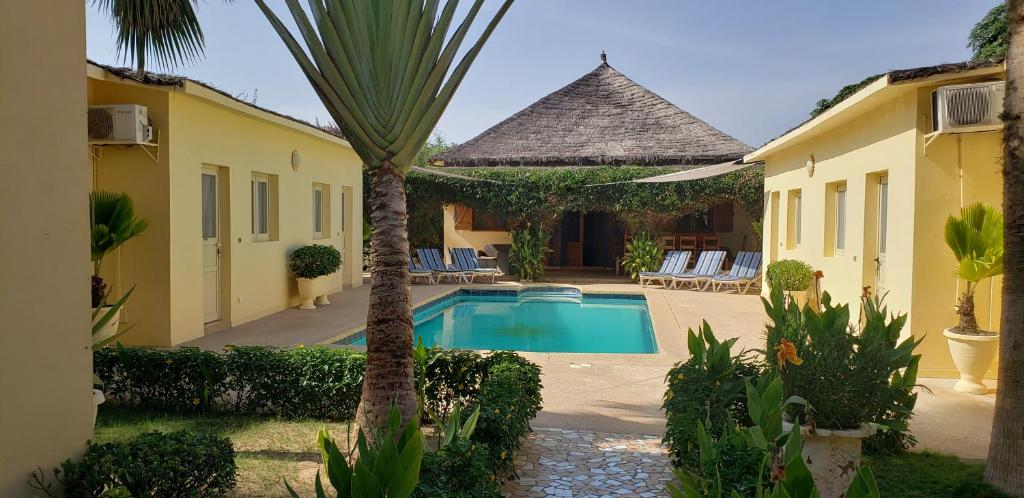 a villa with a swimming pool and a palm tree at Villa Au Soleil in Saly Portudal