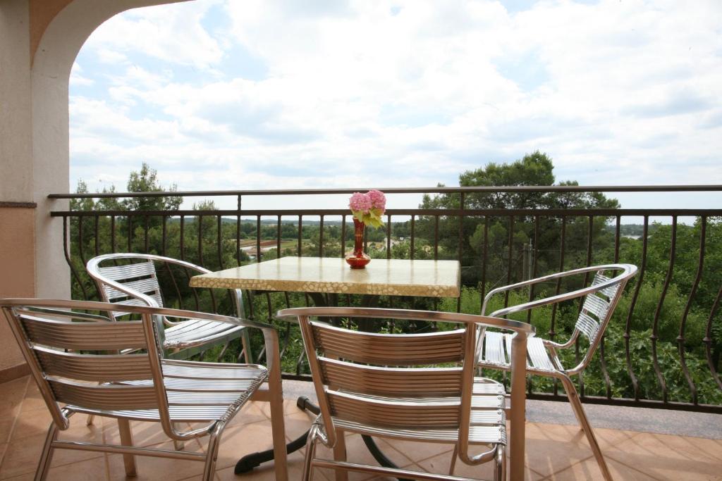 a table with three chairs and a vase of flowers on a balcony at Apartments Neda - Poreč South in Poreč