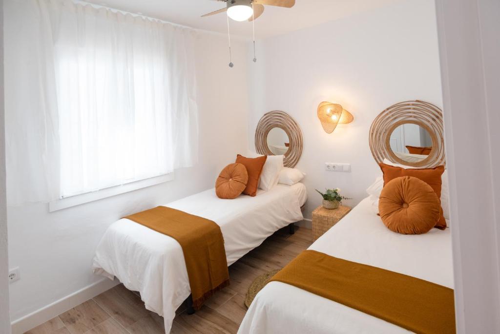 dwa łóżka w pokoju z dwoma lustrami w obiekcie SibsSanlucar MARITIMO-1ª Linea de Playa w mieście Sanlúcar de Barrameda