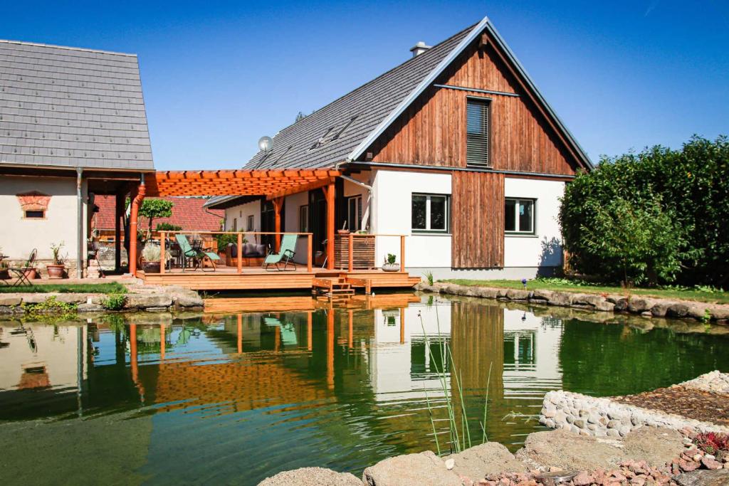 uma casa grande com um lago em frente em AMD Chalet em Stang bei Hatzendorf