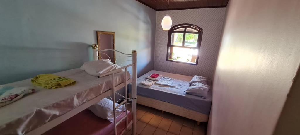 a small room with two beds and a window at Linda Chacara em IBIUNA in Ibiúna
