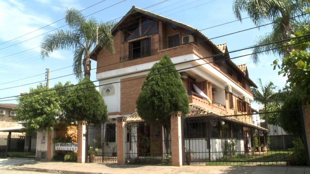 uma casa velha com uma árvore em frente em Dell Osky Pousada em Florianópolis