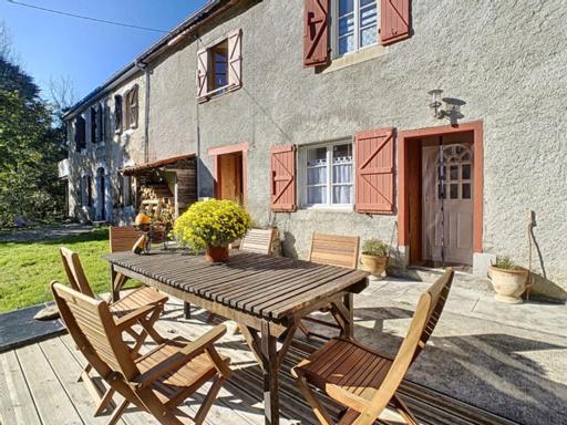 Nistos的住宿－Gîte de montagne « Les Pivoines » à Nistos，房屋前的一张木桌和椅子