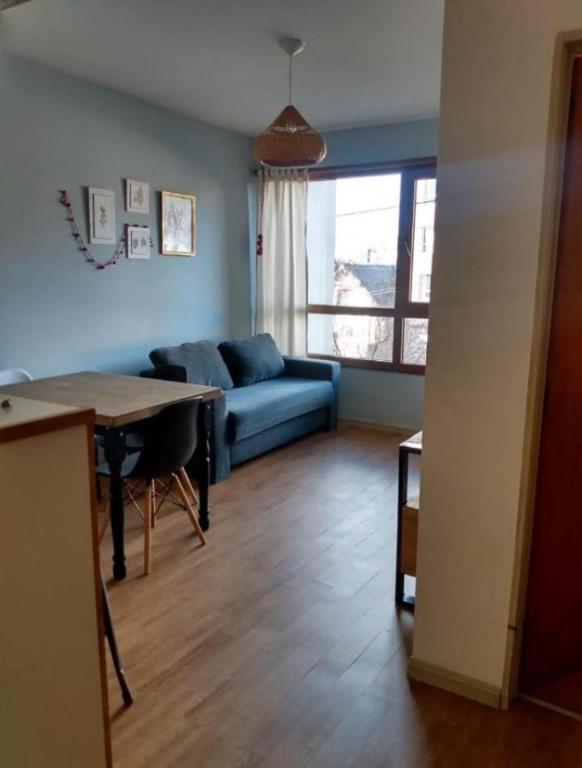een woonkamer met een blauwe bank en een tafel bij Departamento de Barrio Belgrano in Bariloche