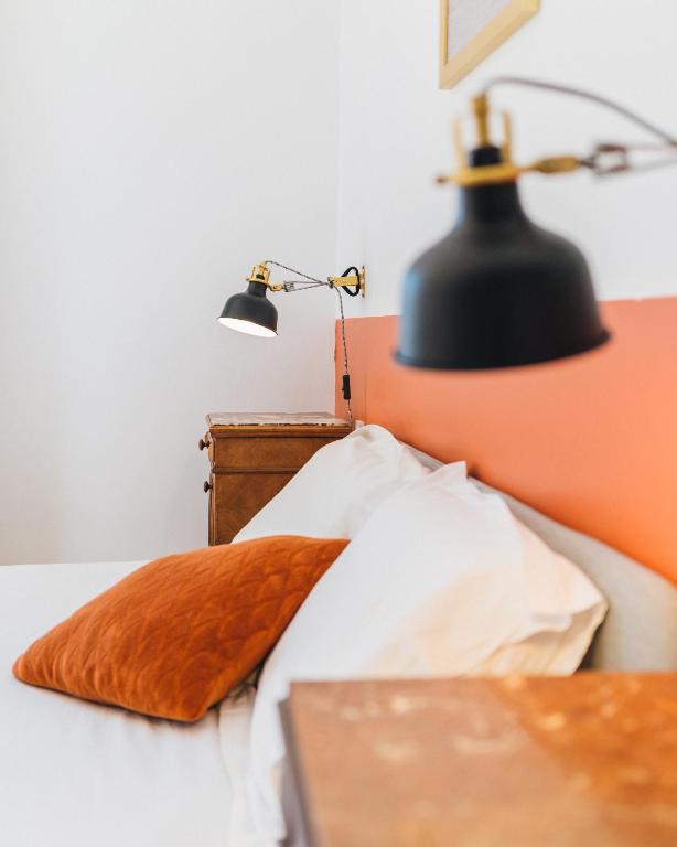 un lit avec une lampe noire et un mur orange dans l'établissement Le Bel Endroit - Joli T2 pour 4 pers, à Bidache