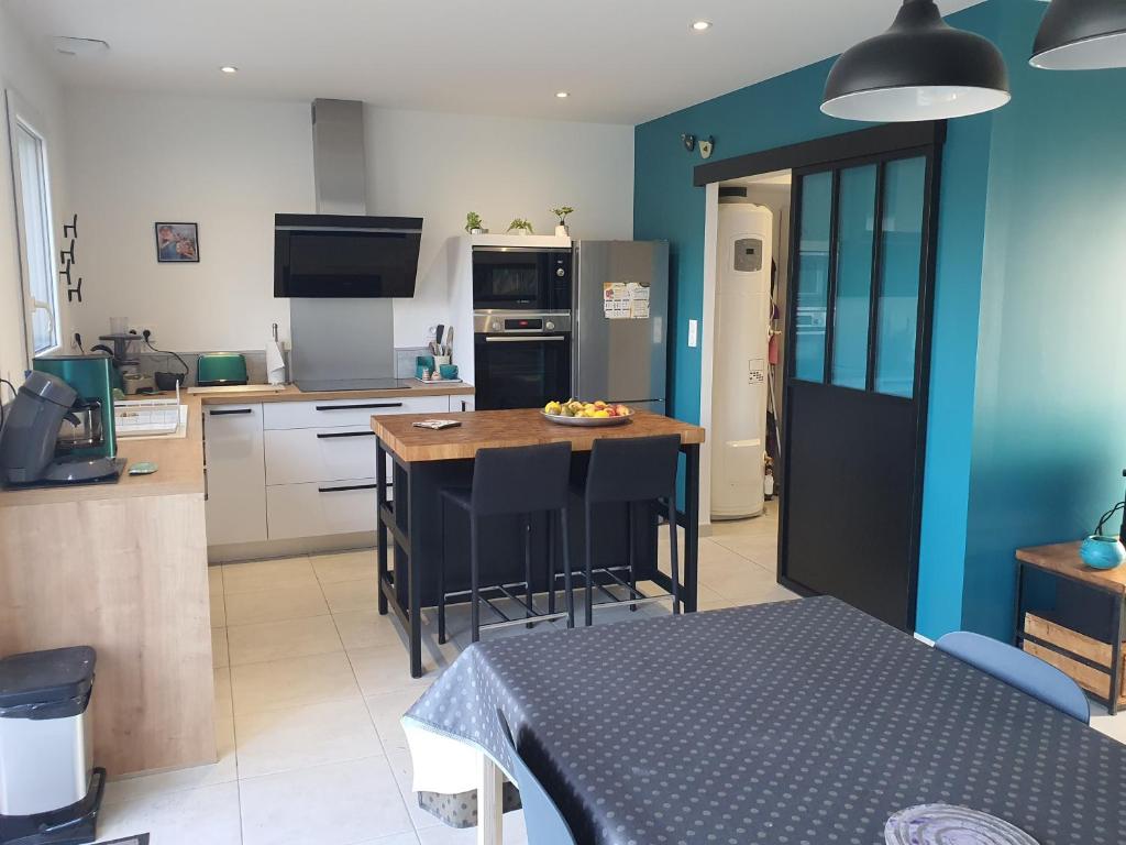 een keuken met een tafel en een keuken met blauwe muren bij LA PETITE SALAMANDRE des Conches in Longeville-sur-Mer