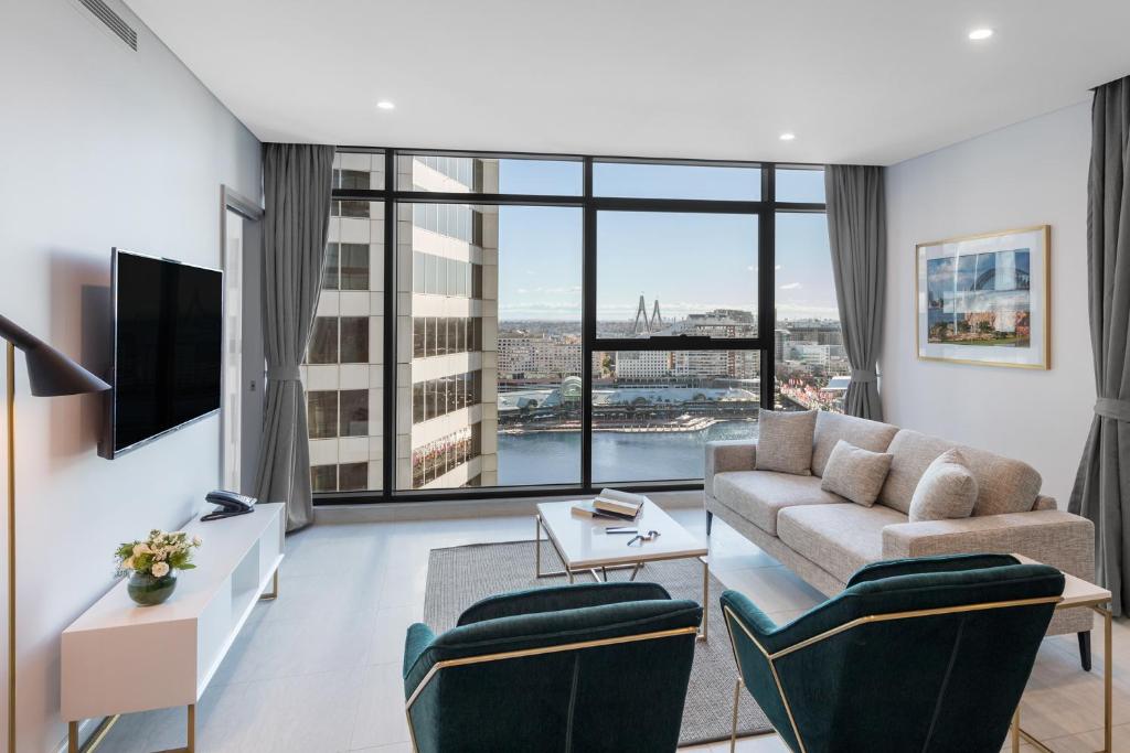 a living room with a couch and a large window at Meriton Suites Sussex Street, Sydney in Sydney