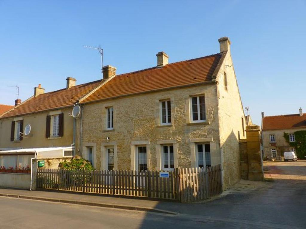 een stenen huis met een hek ervoor bij Maison ancienne entièrement rénovée pour 5 personnes in Bény-sur-Mer