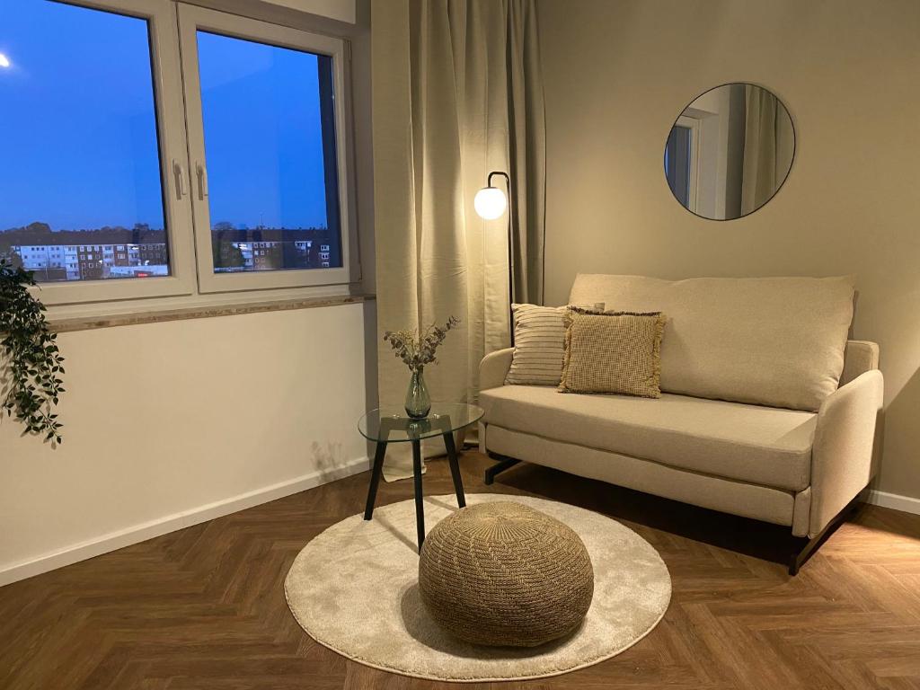 - un salon avec un canapé, une table et une fenêtre dans l'établissement Port 3 - Exklusives City Apartment, à Bremerhaven