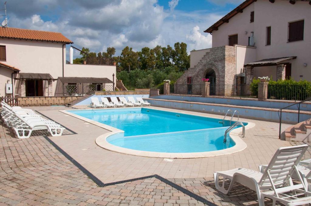 a swimming pool with lounge chairs and a house at Borgo Valmarina in Follonica