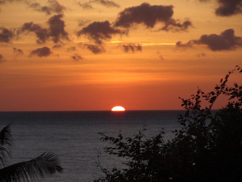una puesta de sol sobre el océano con el sol en el horizonte en Sinar Bali 2, en Amed