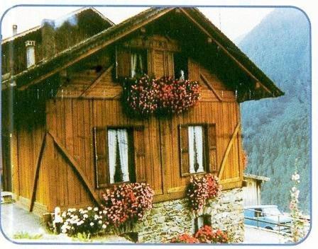 una foto di una casa di legno con dei fiori sopra di Baita Val di Rabbi a Rabbi